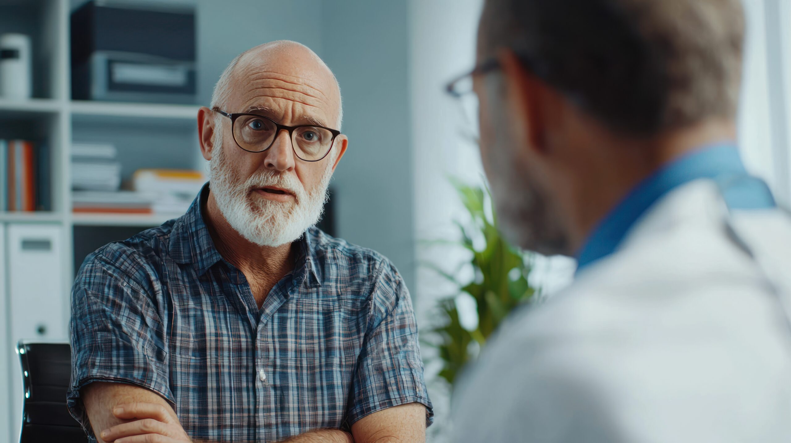 Older man in a doctor’s office, discussing prostate cancer screening options with his urologist.